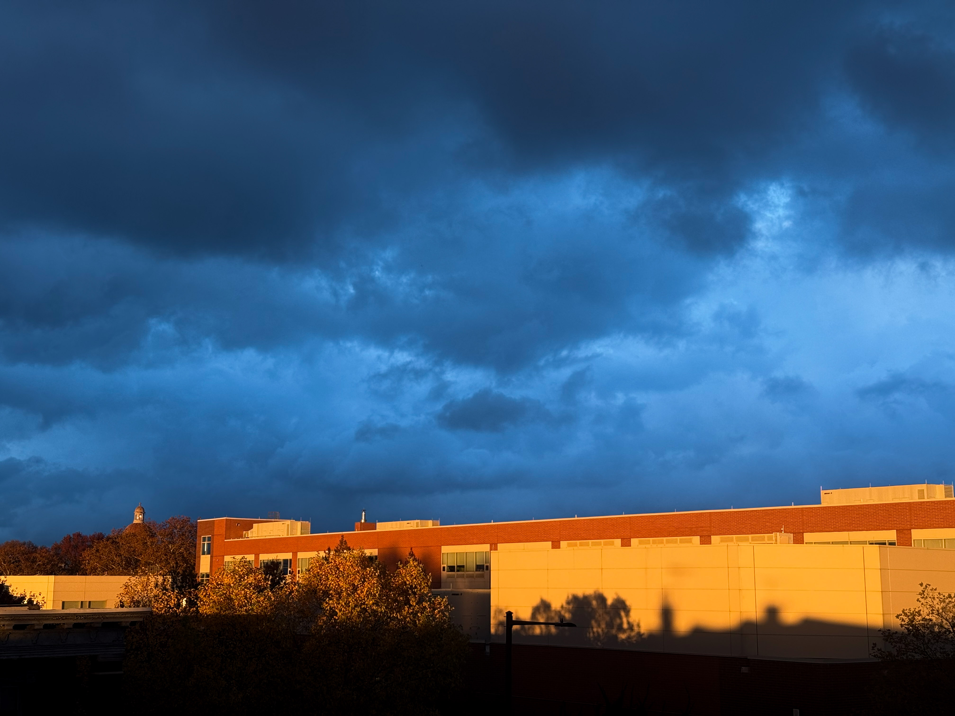 Building illuminated in orange light near sunset, with menacing gray and blue clouds above.