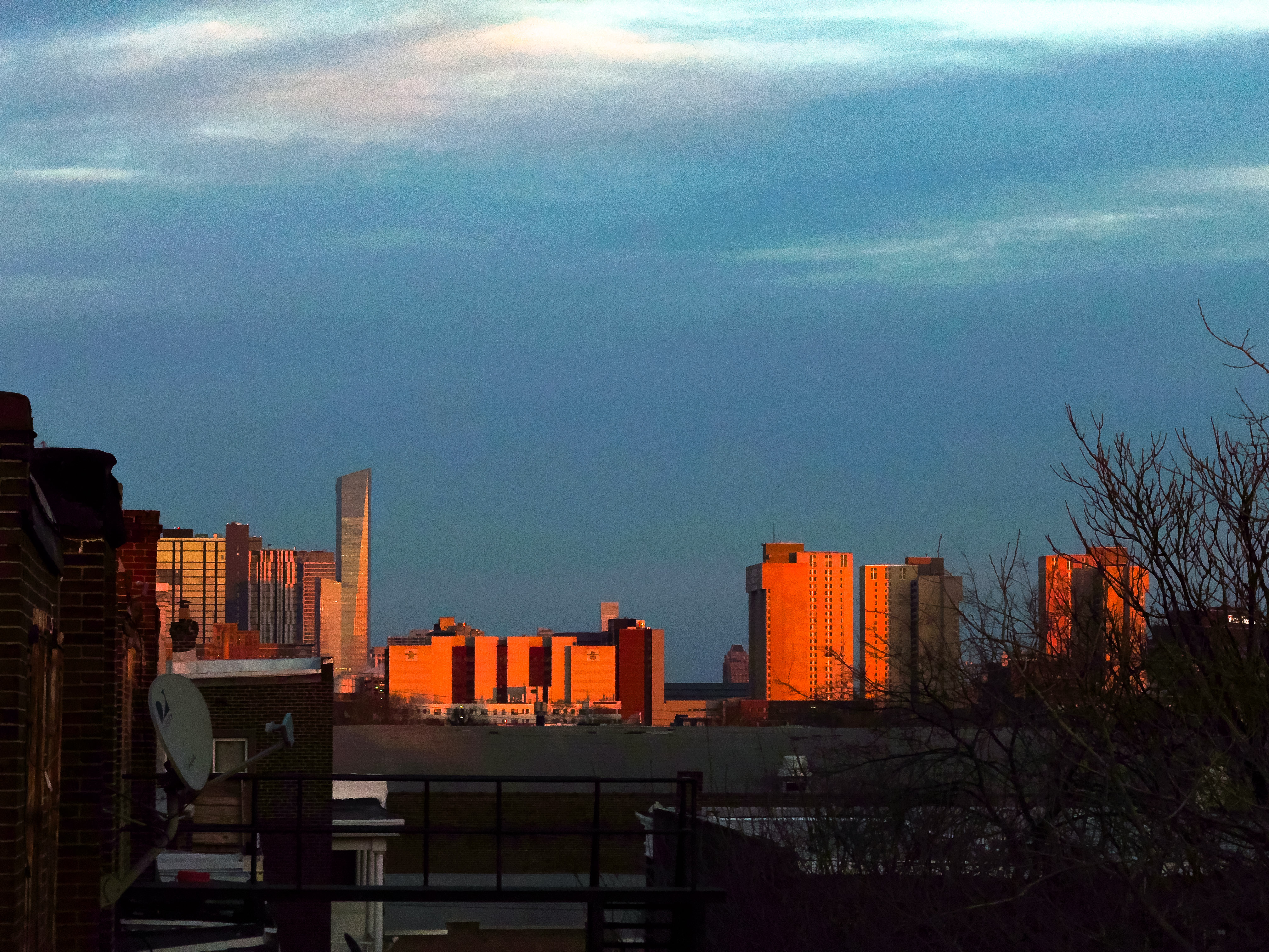 Photograph of Philly buildings around sunset. Orange light reflects off the facades and the sky's cold, blue glow lingers over everything.